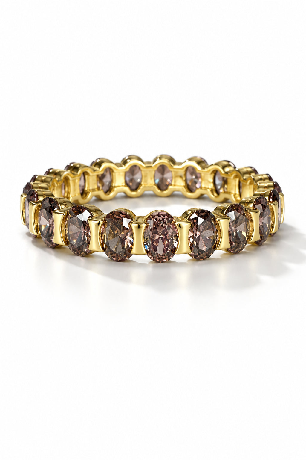 A gold eternity-style ring band featuring a row of oval faceted smoky brown cubic zironiaa, resting on a white background.