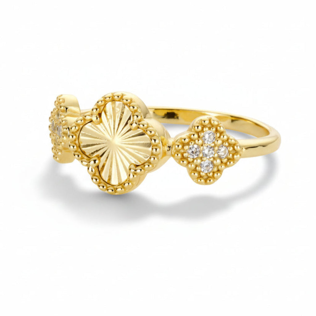 Gold-toned ring with three clover shaped motiffs - one clover with brilliant etching and two pavé cubic zirconia adorned clovers flanking it on a white background