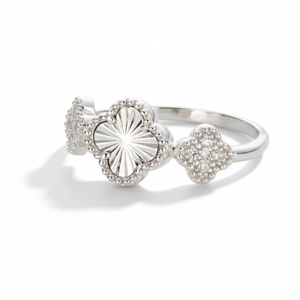 Silver-toned ring with three clover shaped motiffs - one clover with brilliant etching and two pavé cubic zirconia adorned clovers flanking it on a white background