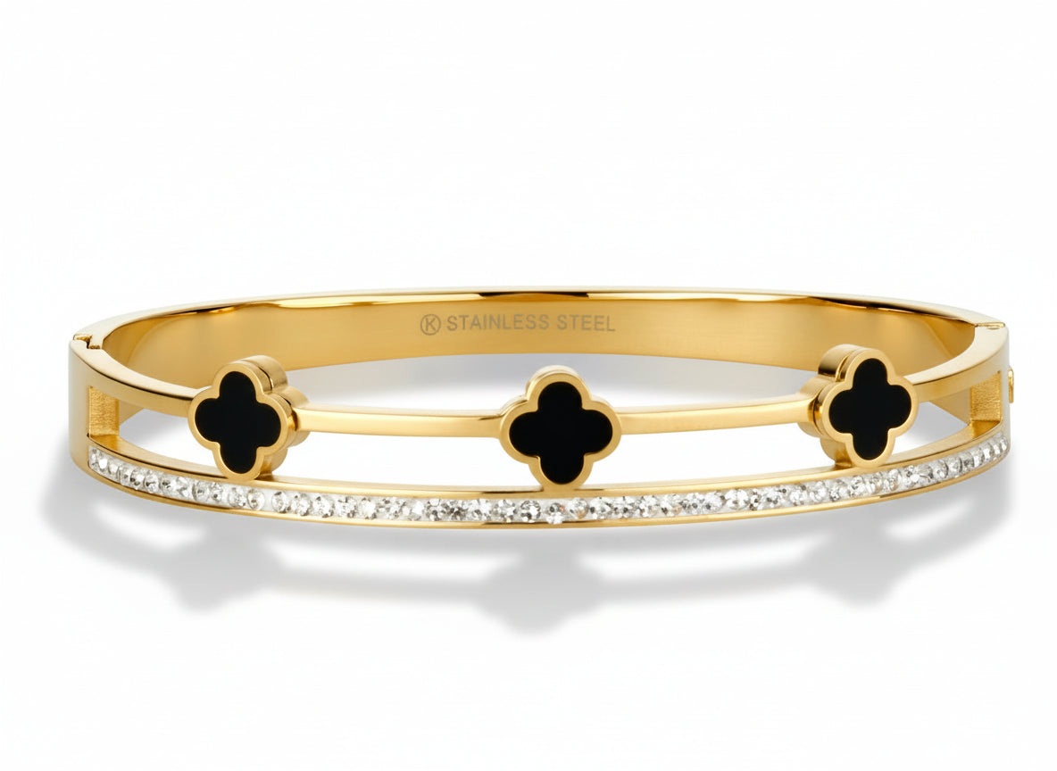 Gold bangle bracelet with black onyx clover designs and cz stones on a white background