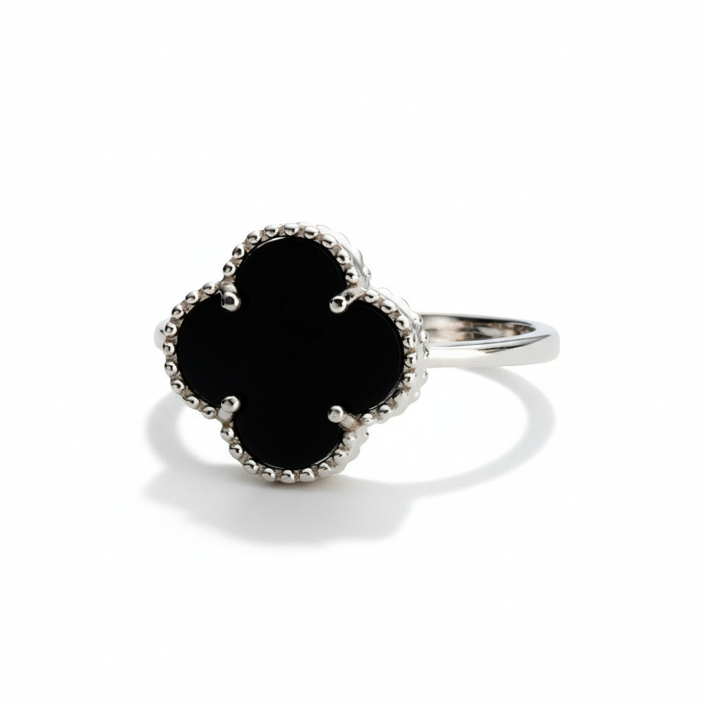 Silver ring with a black clover-shaped gemstone on a white background