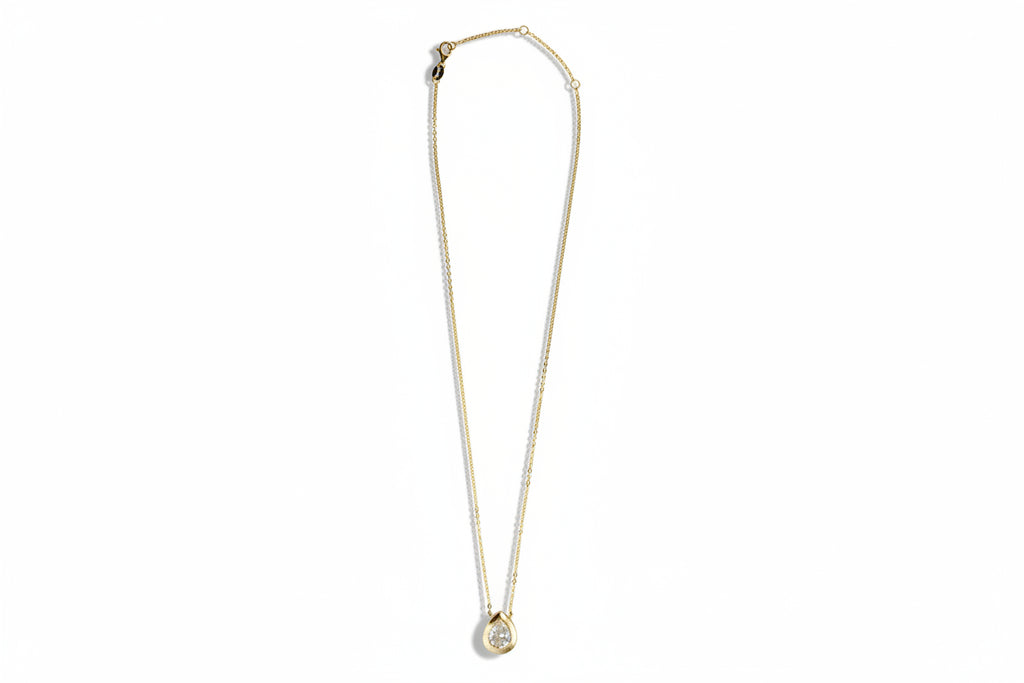 Gold necklace with a cubic zirconia pendant on a white background