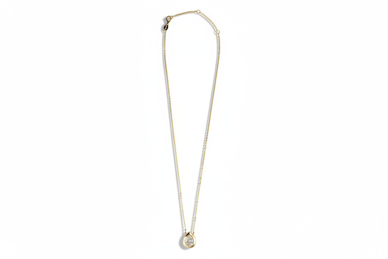 Gold necklace with a cubic zirconia pendant on a white background